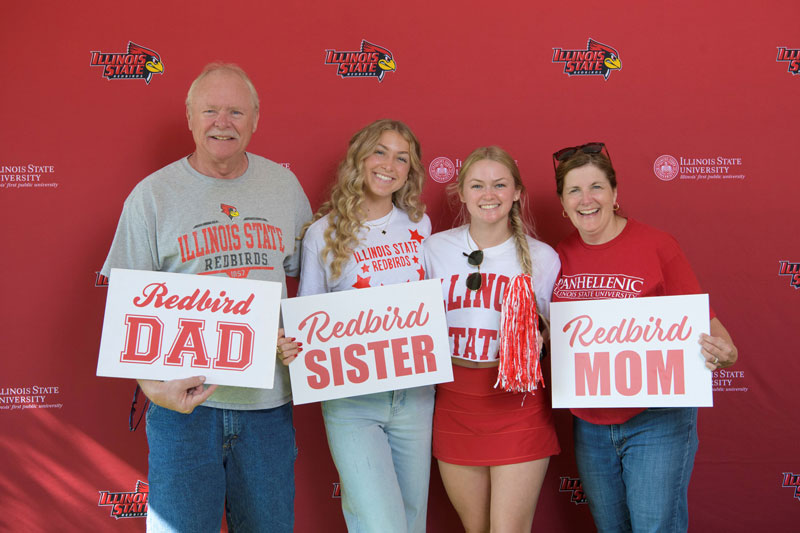 Family posing with ISU Family Weekend printables and ISU flag.